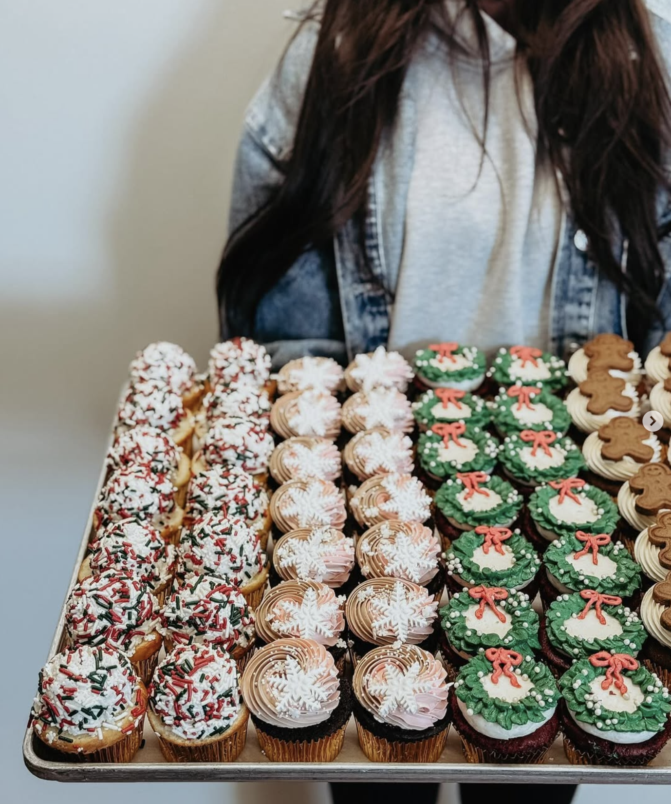 woman holding a tray of holiday cupcakes from Mediterra Café